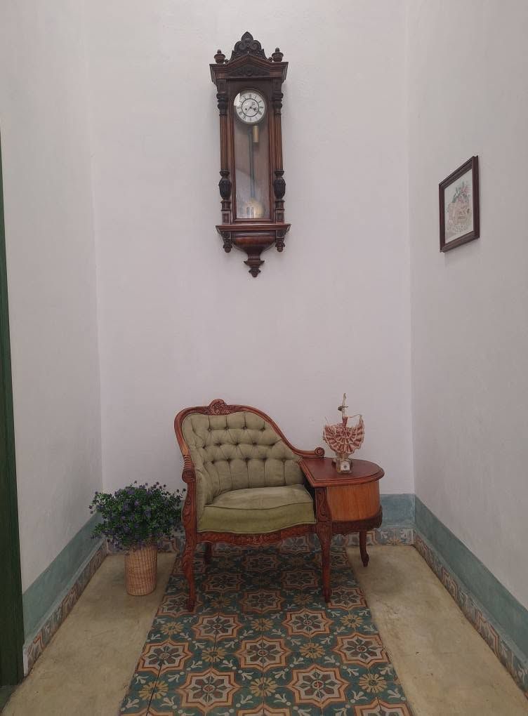 Sillón antiguo y reloj de pared en área común