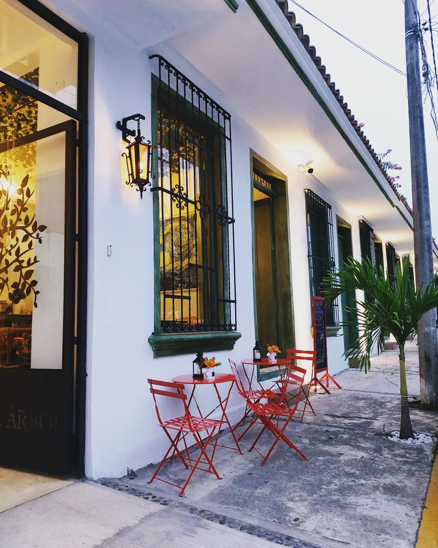 Fachada del hotel con mesas rojas en la banqueta